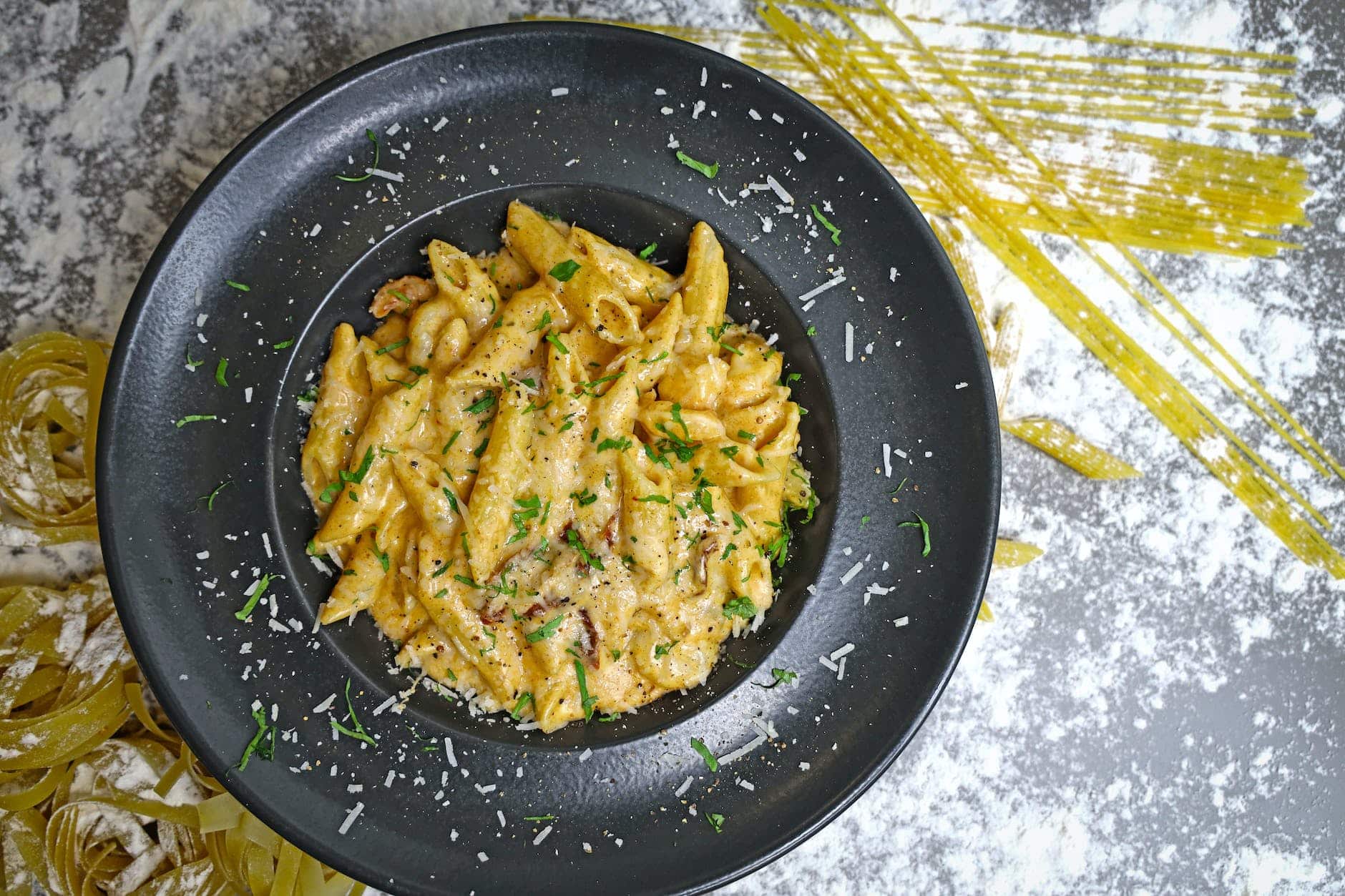 pasta with grated cheese in a black bowl